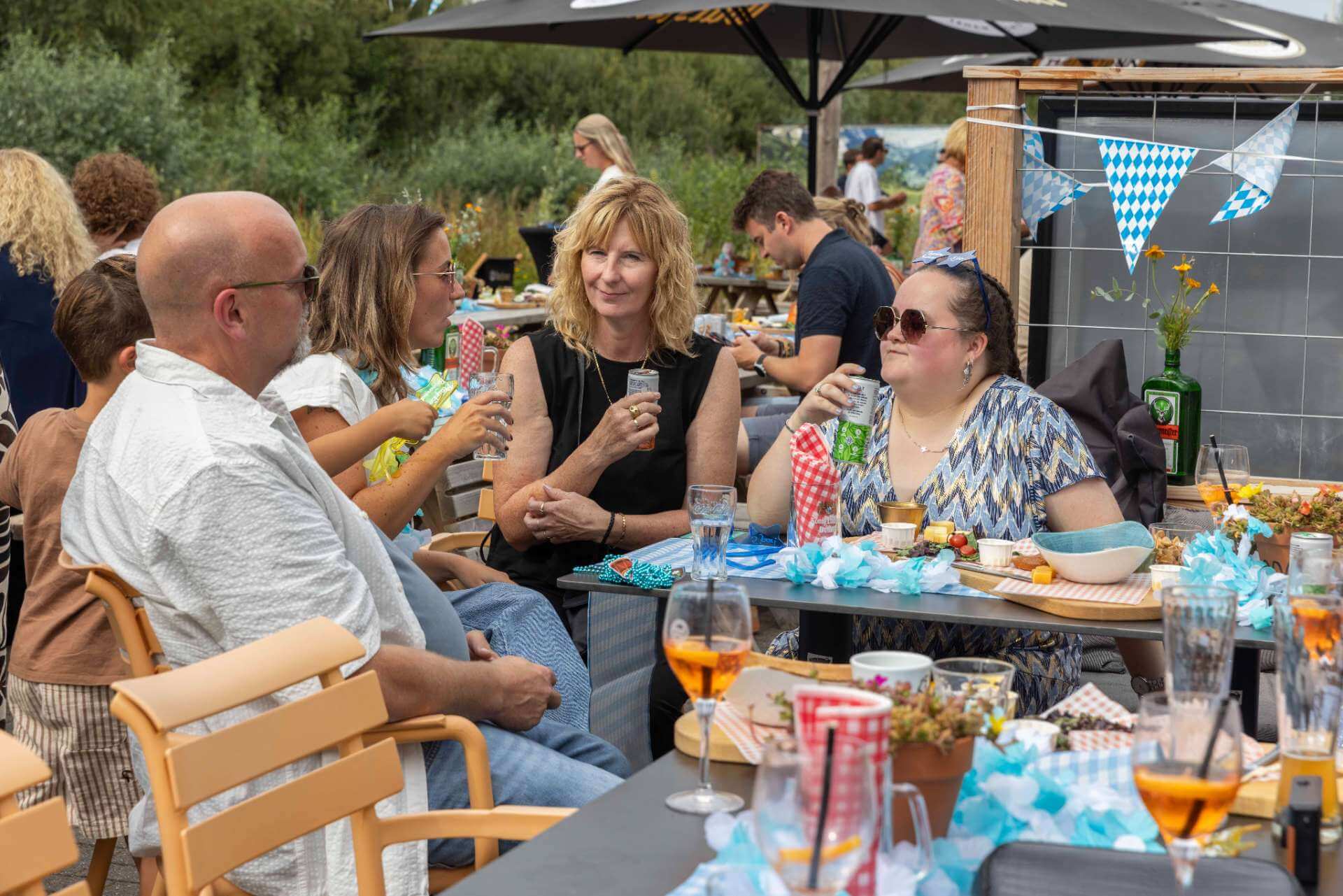 Collega’s zitten samen aan tafel met hapjes en drankjes tijdens een bedrijfsfeest in de Biergarten van Playdôme Roosendaal.